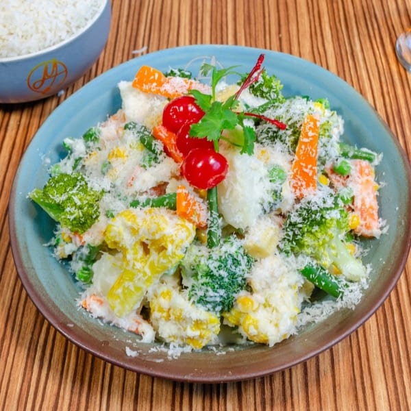 Mausam Indian Flavors' mixed vegetable dish with cheese, garnished with cherries and cilantro.