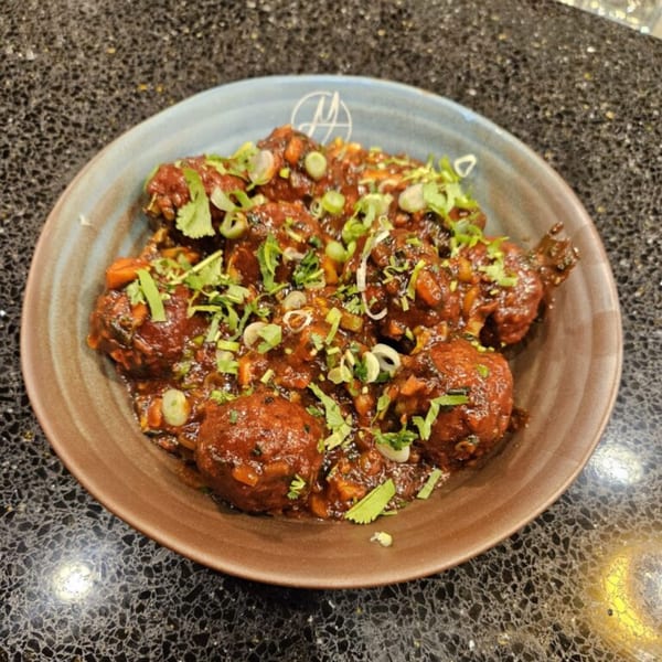 Mausam Indian Flavors' Chicken Lollipop, a popular Indian appetizer, garnished with fresh cilantro and green onions.