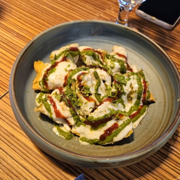 Mausam Indian Flavors' dish of fried dumplings drizzled with white, green, and red sauces, garnished with herbs.