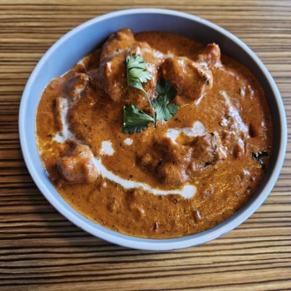 Mausam Indian Flavors' butter chicken, a rich orange curry with chicken pieces, cream swirls, and cilantro.